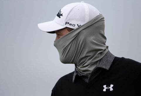 Austria's Bernd Wiesberger covers up against the cold as he leaves the 17th green during his first round 72, on the opening day of the 2015 British Open Golf Championship on The Old Course at St Andrews in Scotland, on July 16, 2015. AFP PHOTO / ADRIAN DENNIS        (Photo credit should read ADRIAN DENNIS/AFP/Getty Images)