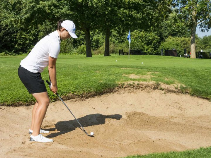 Auch die Technik ist nicht schwer: Richten Sie Ihren Körper nach links von der Fahne aus, das Schlägerblatt des Sand- oder Lob-Wedge zeigt zum Ziel oder leicht nach rechts davon. Der Ball liegt vor der linken Ferse. Schwingen Sie so weit zurück, bis der Schläger senkrecht zum Himmel zeigt – das reicht in der Regel.