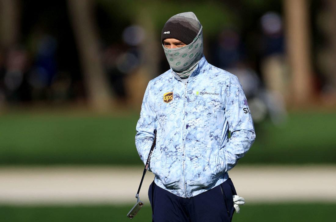 PONTE VEDRA BEACH, tour news, FLORIDA - MARCH 13: Louis Oosthuizen of South Africa waits with his putter after playing his second shot on the par 4, seventh hole wrapped-up against the extreme cold during the weather delayed completion of the second round of THE PLAYERS Championship at TPC Sawgrass on March 13, 2022 in Ponte Vedra Beach, Florida. (Photo by David Cannon/Getty Images)