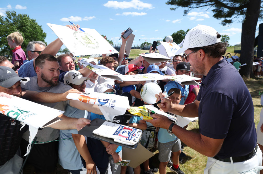 BROOKLINE, MASSACHUSETTS - JUNE 14: Phil Mickelson of the United States signs his autograph for fans near the ninth green during a practice round prior to the US Open at The Country Club on June 14, 2022 in Brookline, Massachusetts. (Photo by Rob Carr/Getty Images)
