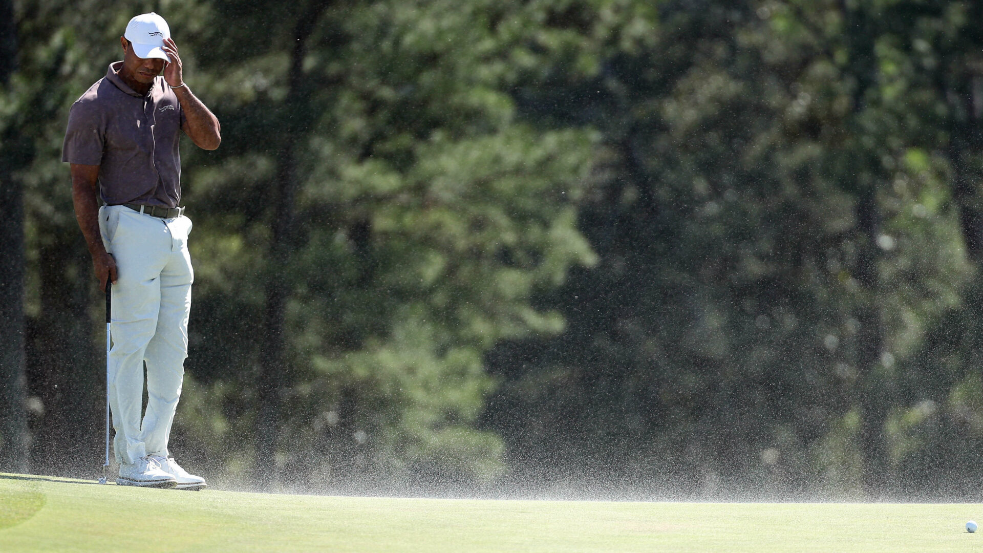 AUGUSTA, GEORGIA - APRIL 12: Tiger Woods of the United States shields his face from the blowing sand on the 18th green during the second round of the 2024 Masters Tournament at Augusta National Golf Club on April 12, 2024 in Augusta, Georgia. (Photo by Warren Little/Getty Images)