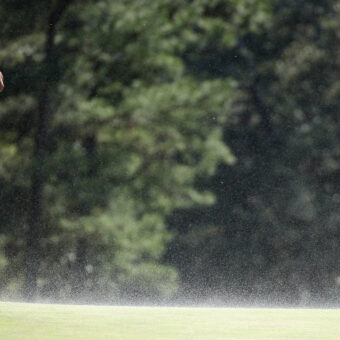 AUGUSTA, GEORGIA - APRIL 12: Tiger Woods of the United States shields his face from the blowing sand on the 18th green during the second round of the 2024 Masters Tournament at Augusta National Golf Club on April 12, 2024 in Augusta, Georgia. (Photo by Warren Little/Getty Images)