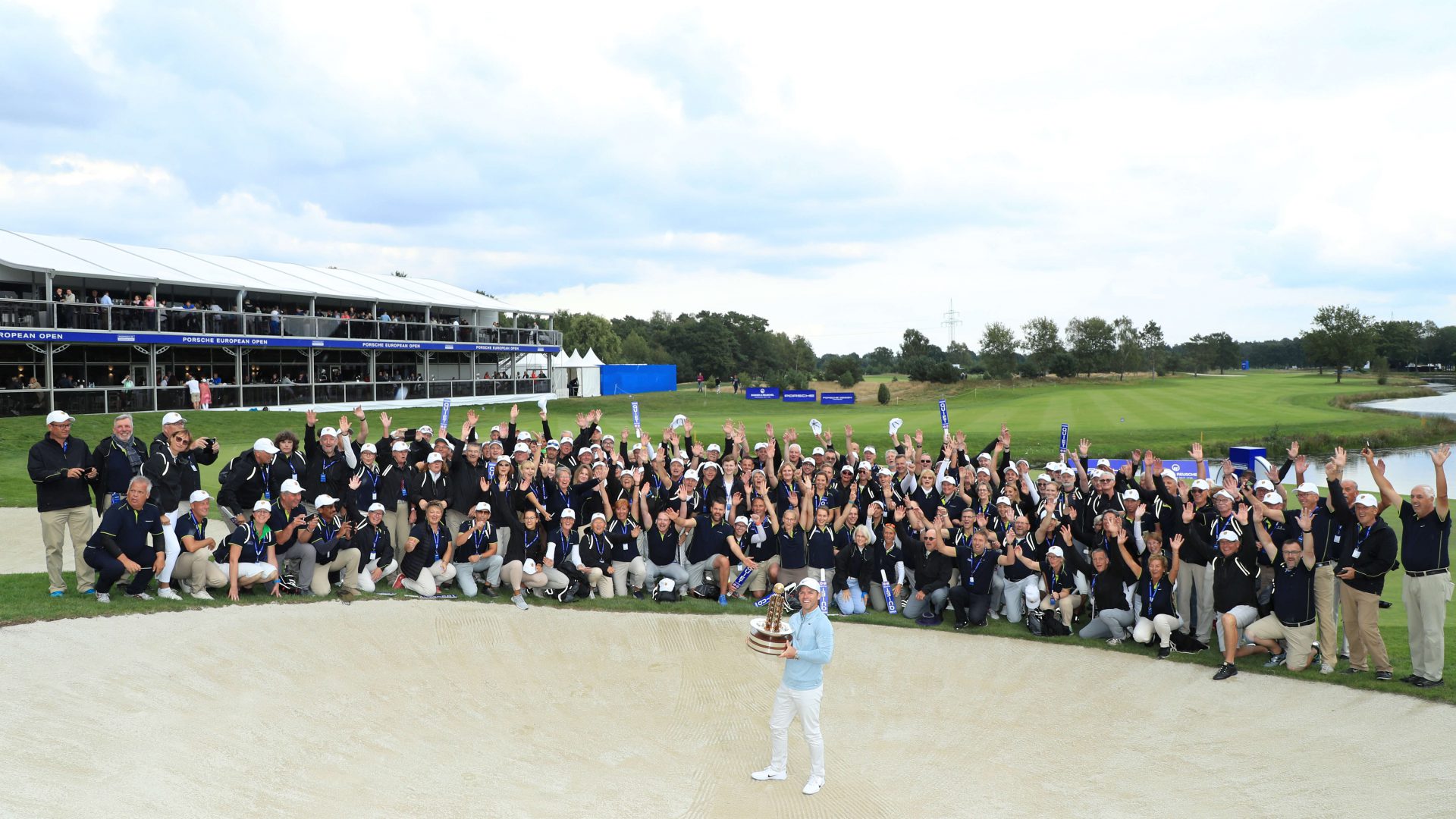Paul Casey of England celebrates with the trophy in front of volunteers following Day 4 of the Porsche European Open at Green Eagle Golf Course on September 08, 2019 in Hamburg, Germany