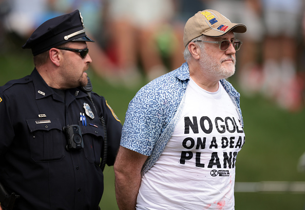 CROMWELL, CONNECTICUT - JUNE 23: Climate change protestors are ushered off the 18th green by police officers during the final round of the Travelers Championship at TPC River Highlands on June 23, 2024 in Cromwell, Connecticut. (Photo by James Gilbert/Getty Images)