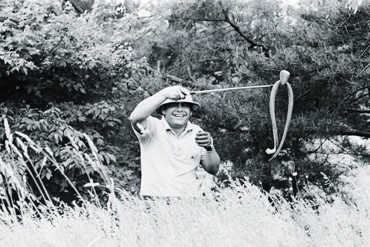 (Original Caption) Ardmore, PA: Hammin' it up in the rough of the Merion Country Club, Lee Trevino pulls a snake out of the grass with his club much to the amazement of the spectators. Trevino, a golf comedian, has dropped the toy snake from his pocket to set up the joke. 6/16/1971